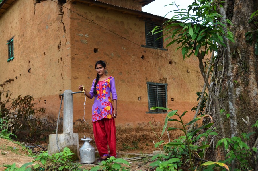 Sushmita using the tap and filling a gagri, a traditional Nepalese water vessel.