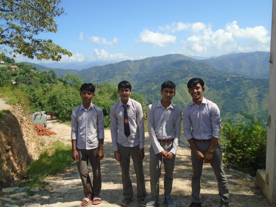 Bishal, Suraj, Nabin and Bikram stand outside in front of the mountains. 