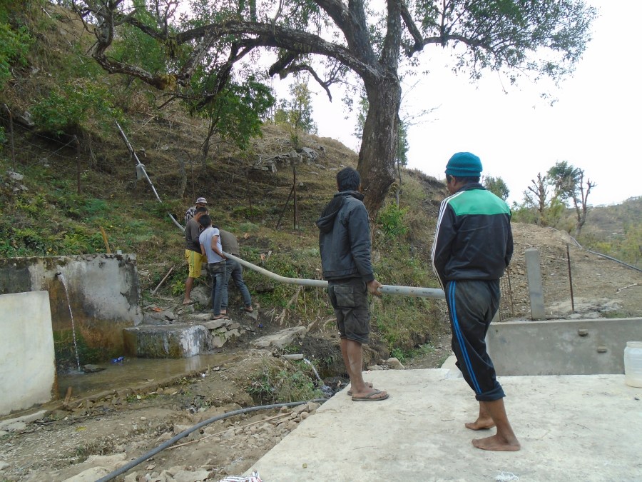 Community members work together on the piping which is taking place and installed on a hill in Jugedhara.