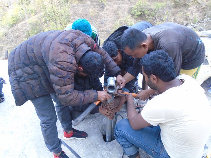 All hands to the pump as five men work together to install some of the final details on the piping.