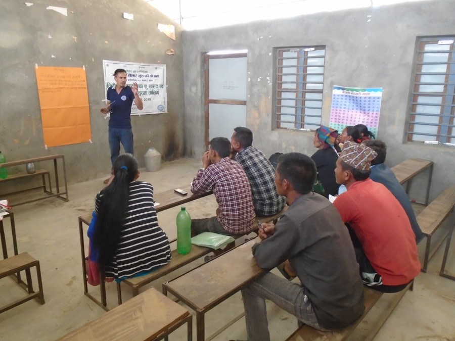 Training on water resource management and health and safety, led by a project worker, with many community members.