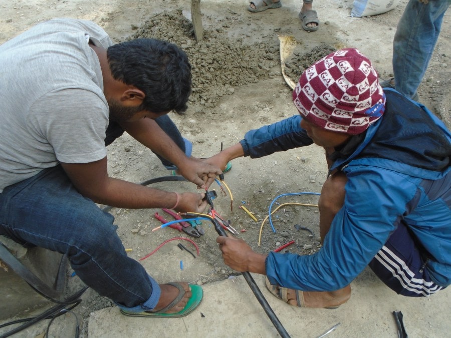 Two men work together on Intricate and careful wiring for the pump. 