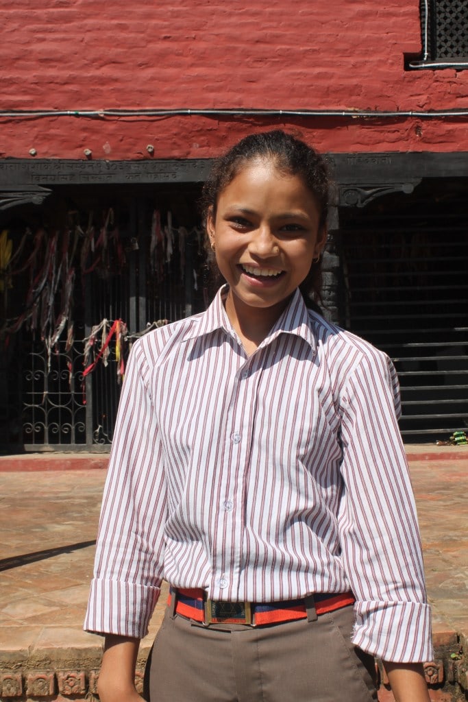 Deepa smiling in front of the school. 