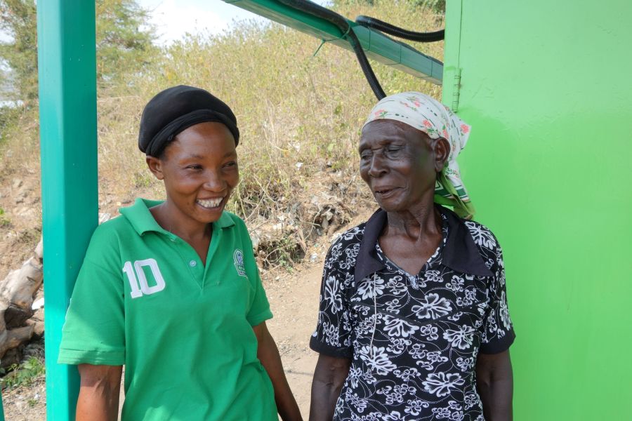 Diana smiling in front of the energy hub with a member of the community. 