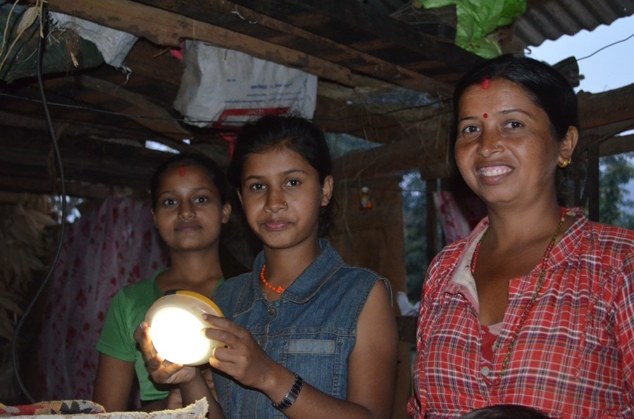 A young girl and her family with a solar-light that they received from Renewable World as part of the Earthquake Relief project