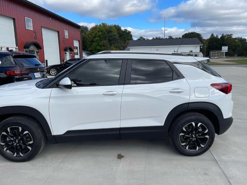 White compact SUV with tinted windows and black wheels outside auto dealership.