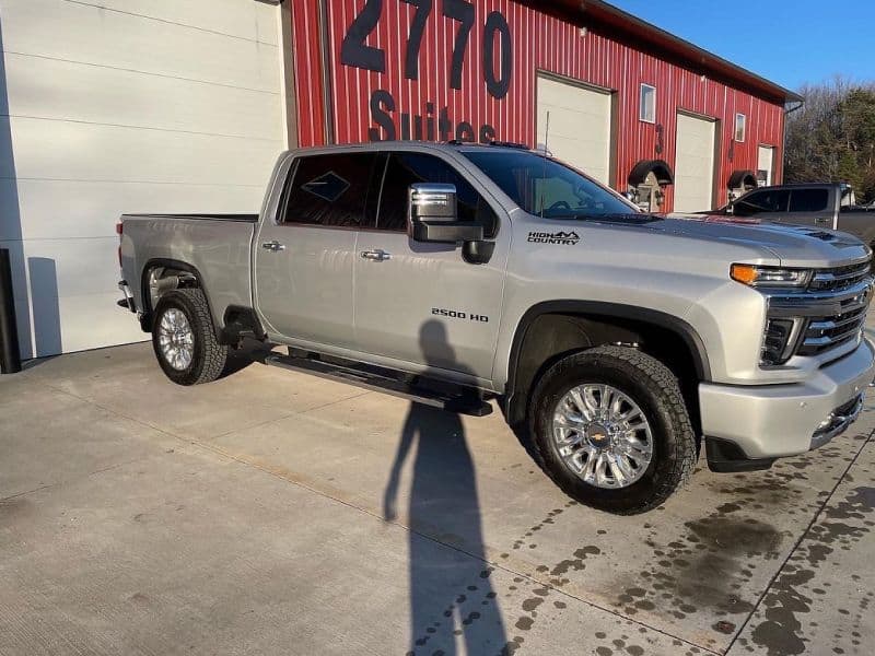 Silver Chevrolet Silverado 2500 HD pickup truck parked outside a red building.