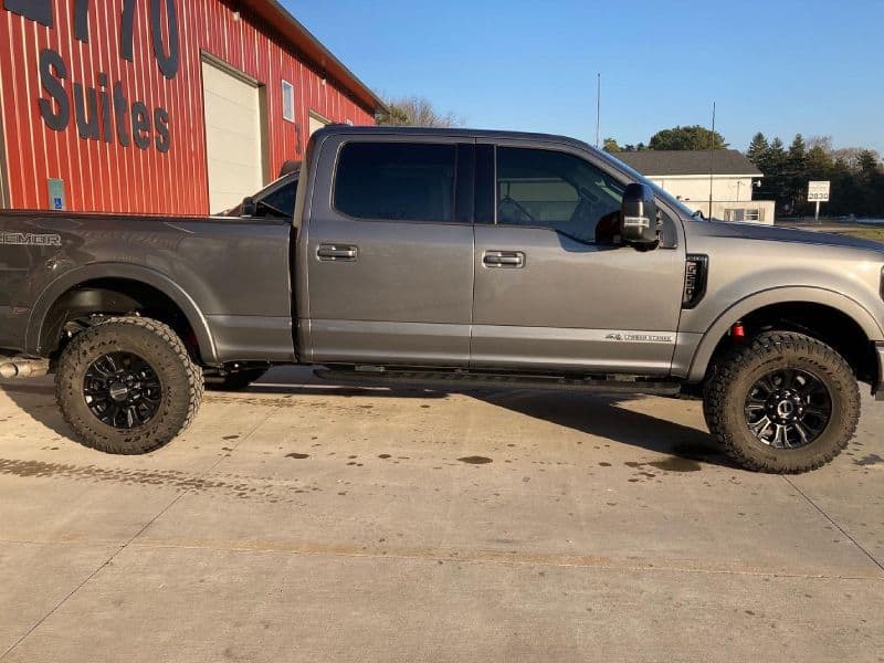 Gray Ford F-250 Super Duty pickup truck parked outside a red building.