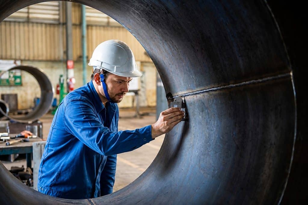 NDT technician inspecting the interior of a large industrial pipe for defects.