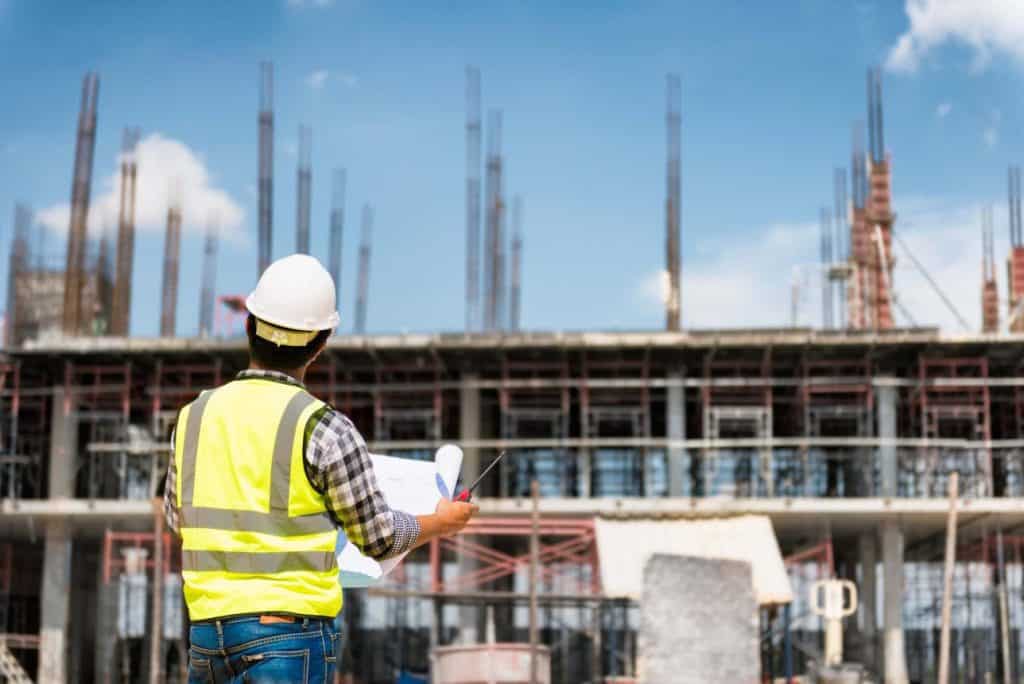 Construction inspector reviewing plans at a government or educational building site.