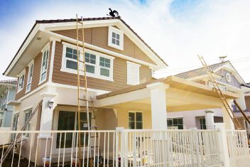 Modern house exterior with new siding, windows, and porch under construction.