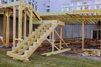 Wooden staircase and deck framework under construction at a residential property.