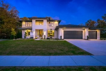 Two-story house with siding, large windows, and attached garage at dusk.