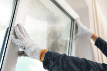 Technician installing a window with gloves for insulation and protection.