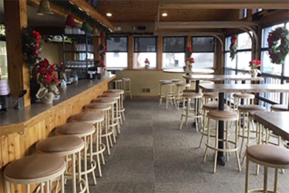 Empty bar and dining area with wooden furniture and holiday decorations.