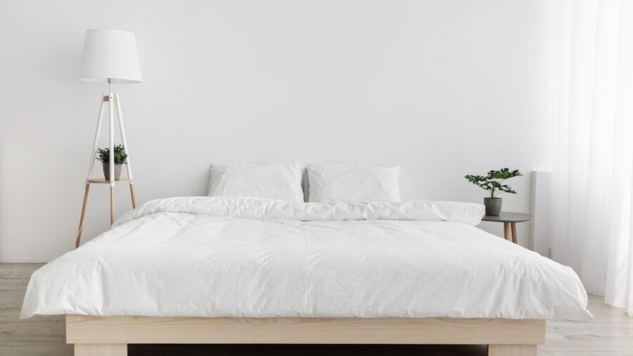 Šviesus minimalistinio stiliaus miegamojo interjeras su lova ir naktiniu staliuku