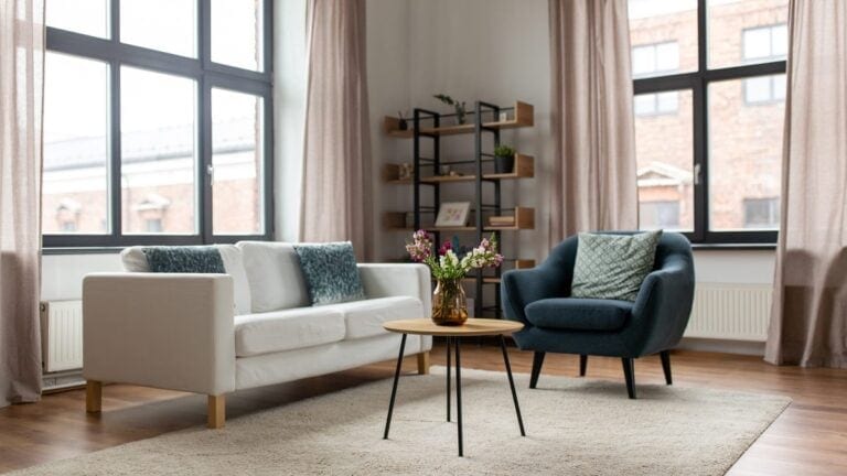 Jauki svetainė su minkšta sofa ir dekoratyvinėmis pagalvėlėmis eklektiško stiliaus interjere