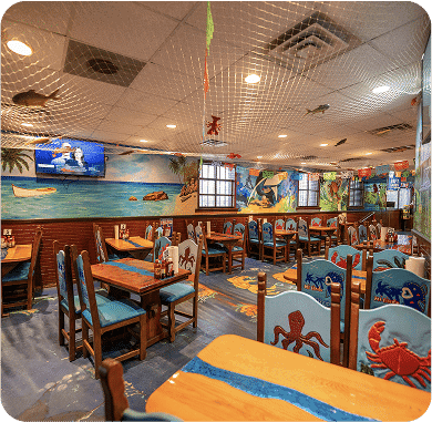 Interior of a tropical-themed restaurant with ocean murals and wooden furniture.