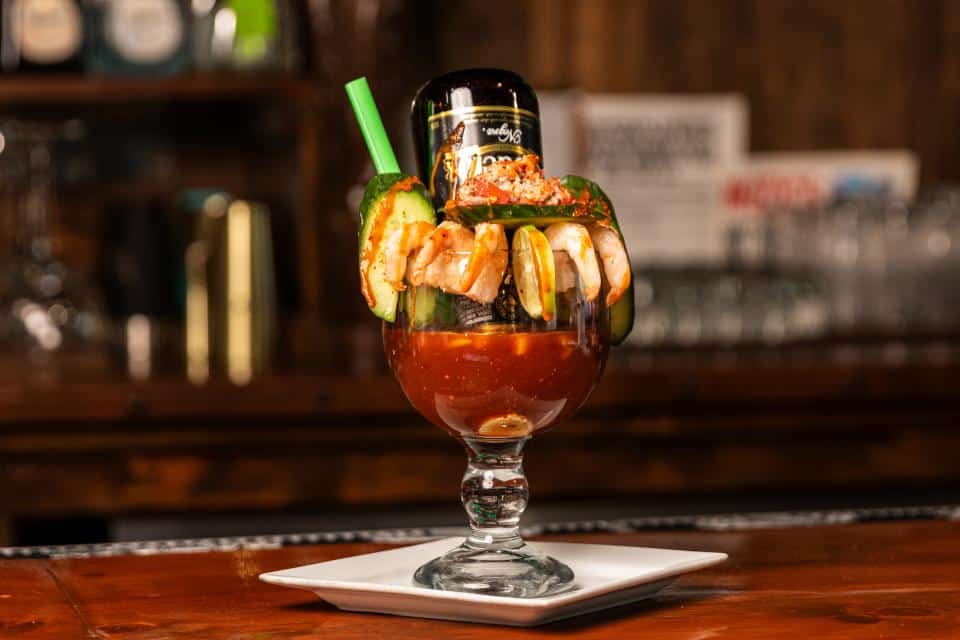 Colorful cocktail with shrimp, lime, and vegetables in a glass.