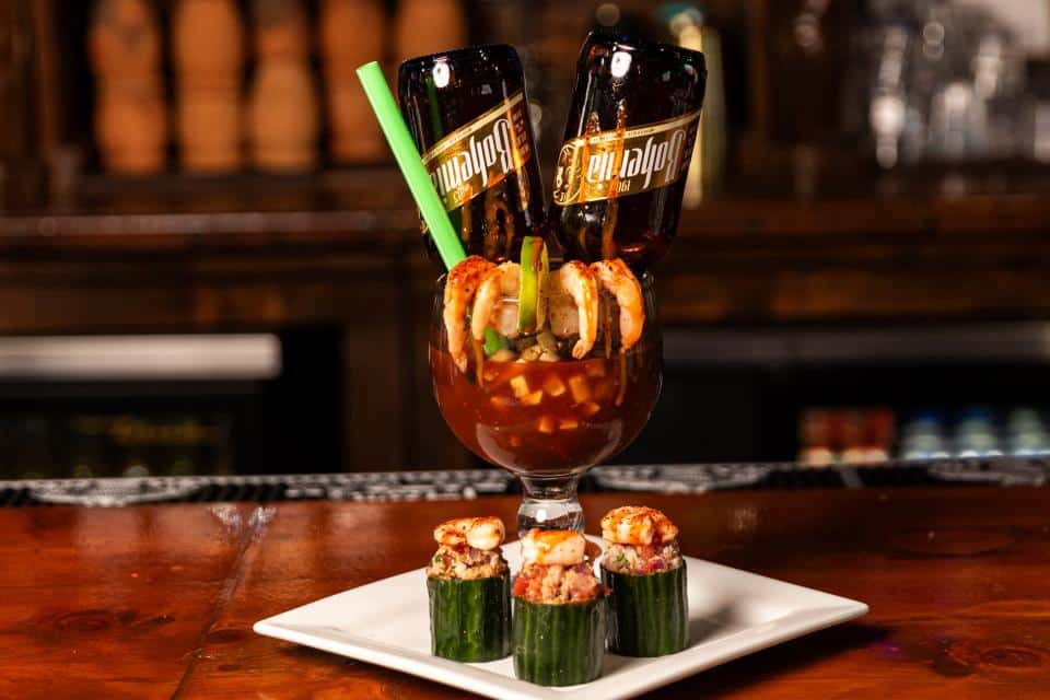 Cocktail with sushi rolls and drinks on a bar counter.