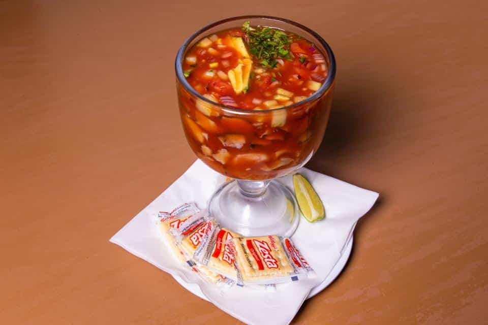 Seafood cocktail with octopus, vegetables, and lime in a glass.