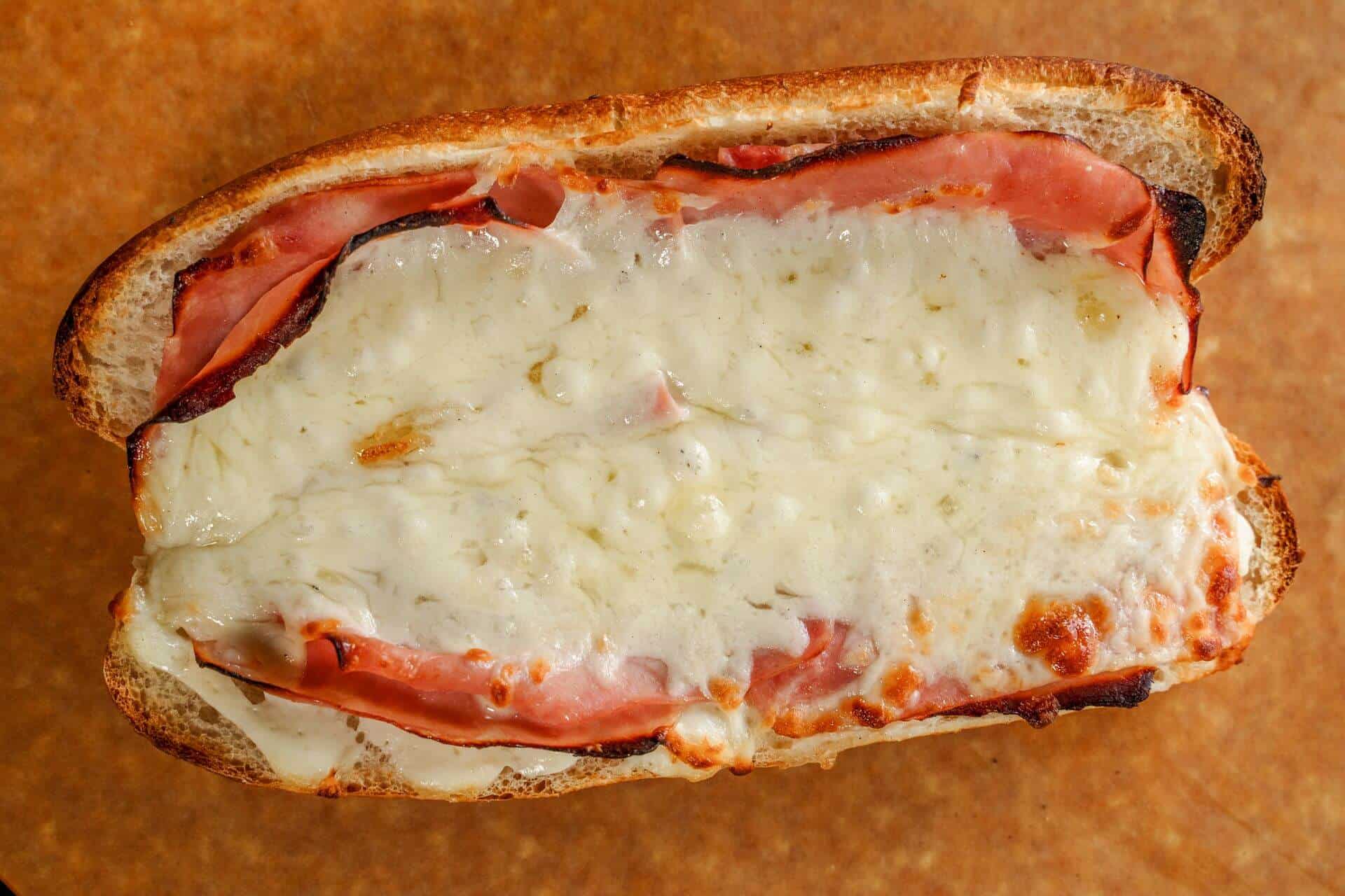 Close-up of a Sicilian pizza with cheese and ham on thick crust.