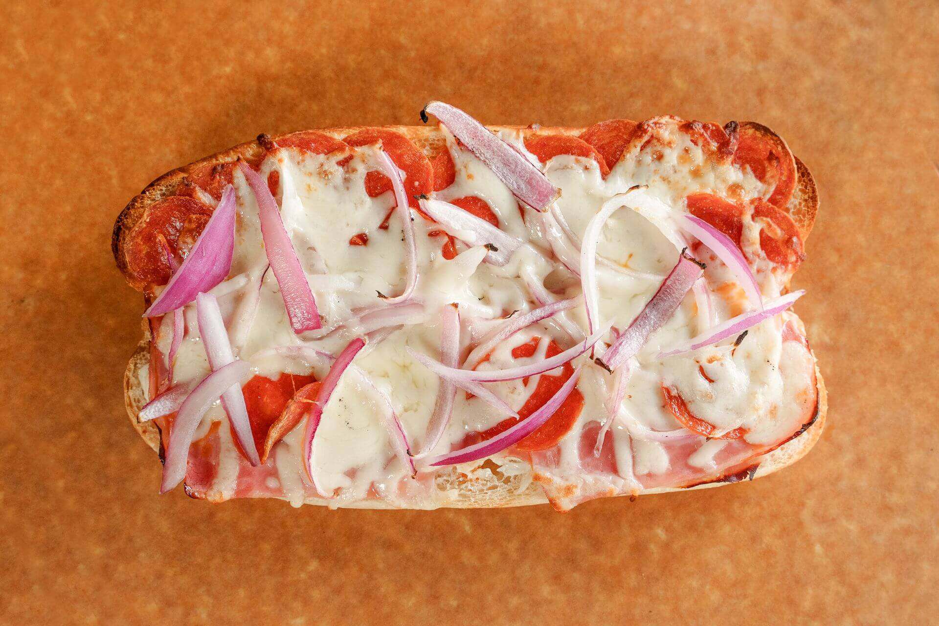 Close-up of a Sicilian pizza with cheese, tomato sauce, and onions.