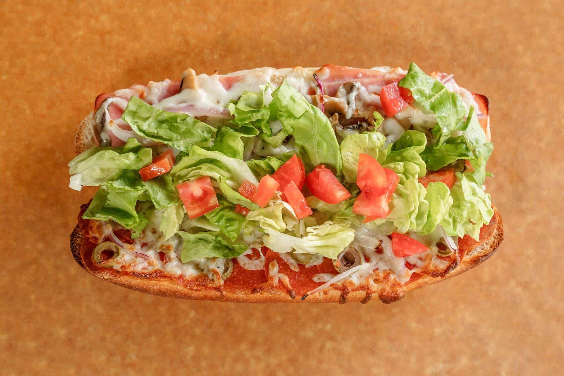Close-up of a Sicilian pizza with lettuce, tomatoes, and cheese.