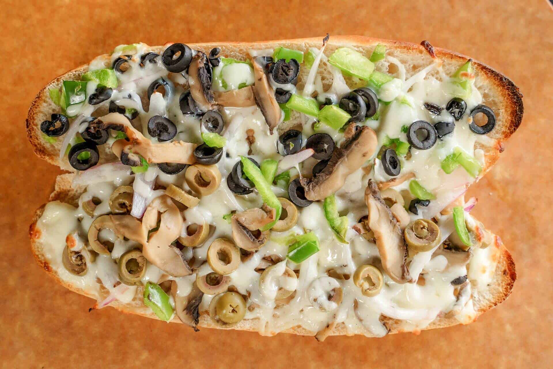 Close-up of a Sicilian pizza slice with mushrooms, green onions, and cheese.