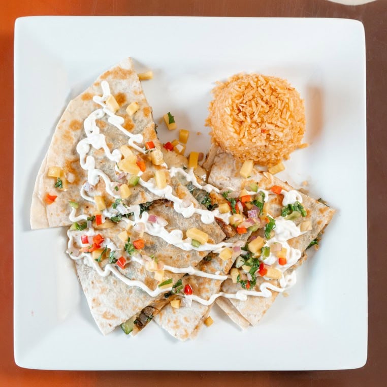 Tacos with fried ball, colorful vegetables, and creamy sauce on white plate.