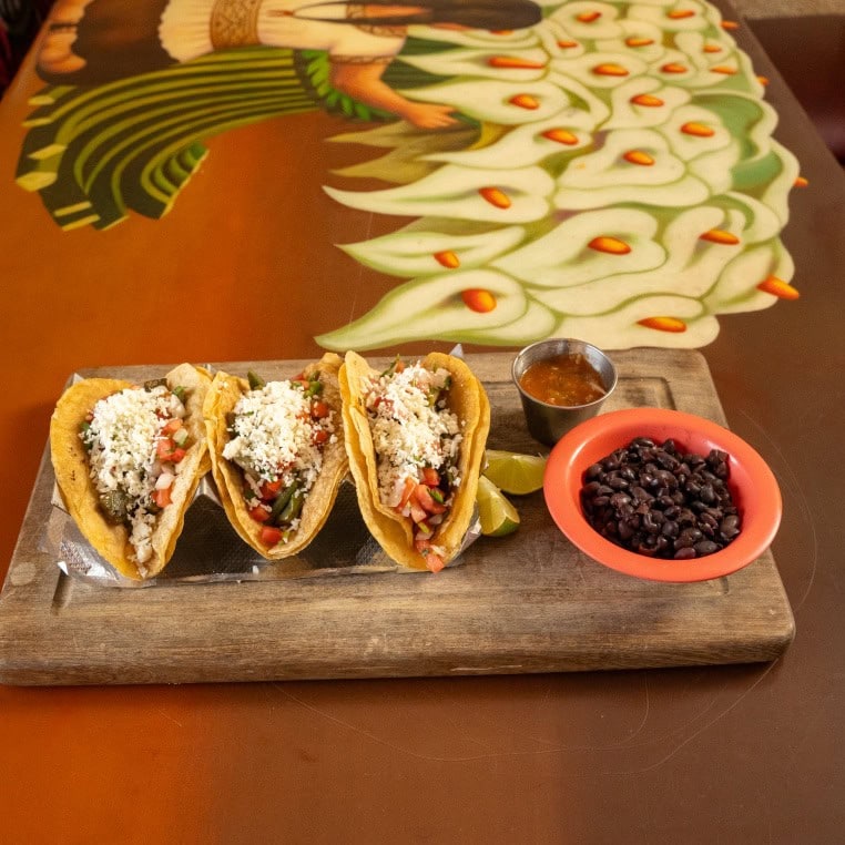 Tasty tacos filled with vegetables, cheese, and meat, served with black beans and salsa on a wooden.