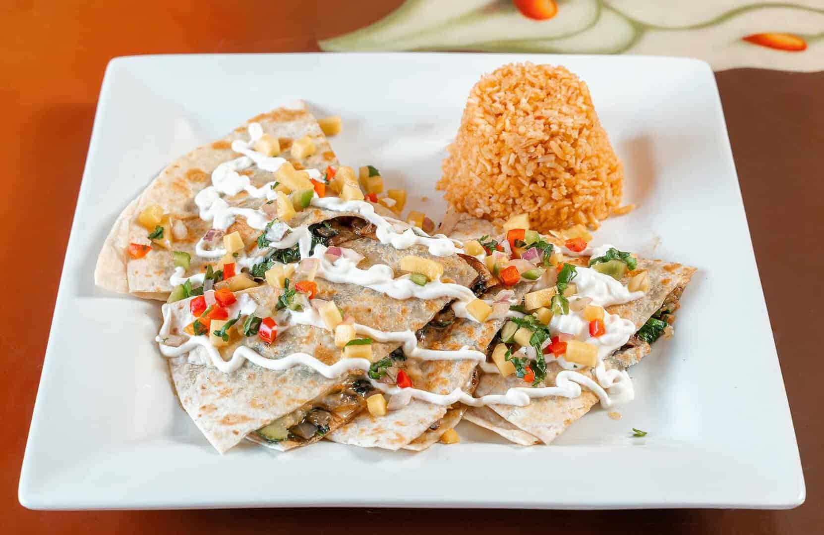 Delicious Mexican chicken tacos with rice, garnished with fresh vegetables and creamy sauce.