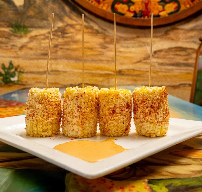 Cornbread appetizer with honey drizzle on a white plate.
