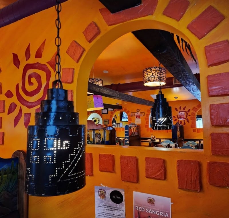 Bright orange restaurant with colorful wall art and unique lighting fixtures.