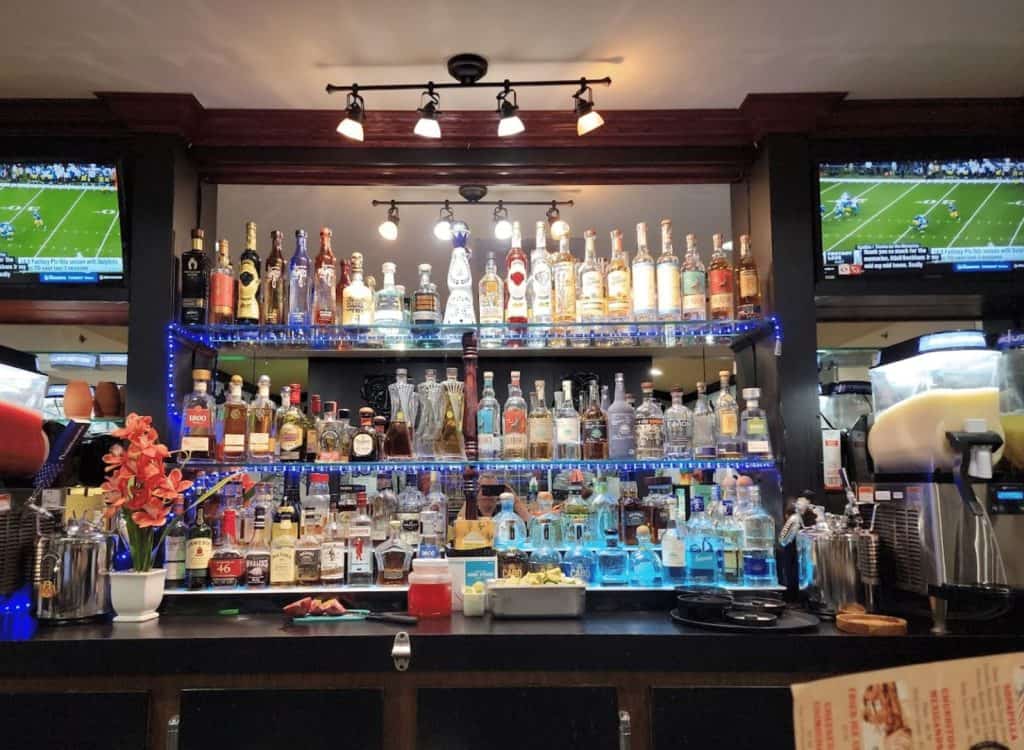 Bar with liquor bottles and football screens for sports viewing.