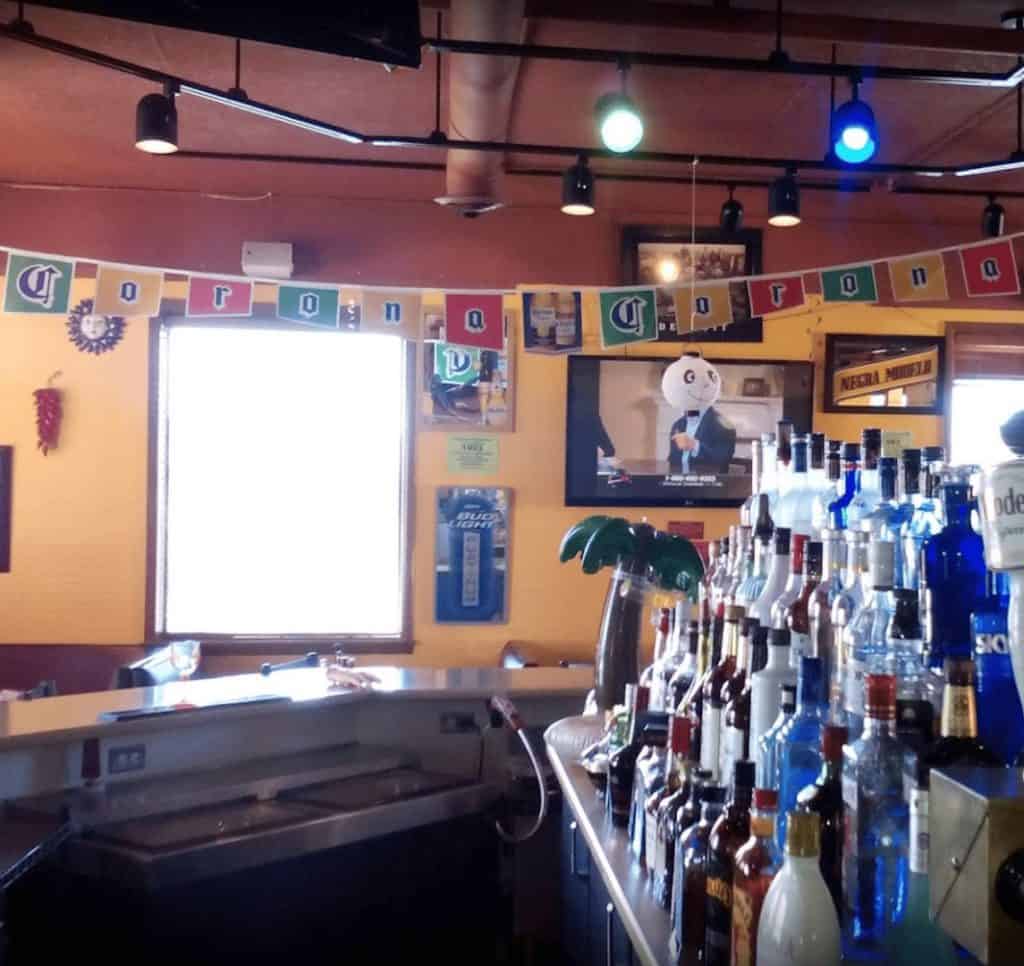 Bar with liquor bottles and colorful decor in a restaurant setting.