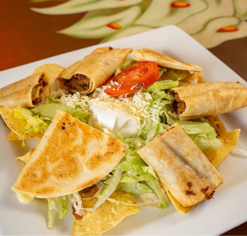 Crispy beef spring rolls served with fresh salad and tomatoes on a white plate.