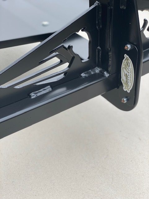 Close-up of a black metal frame with a gold emblem and mounting hardware.