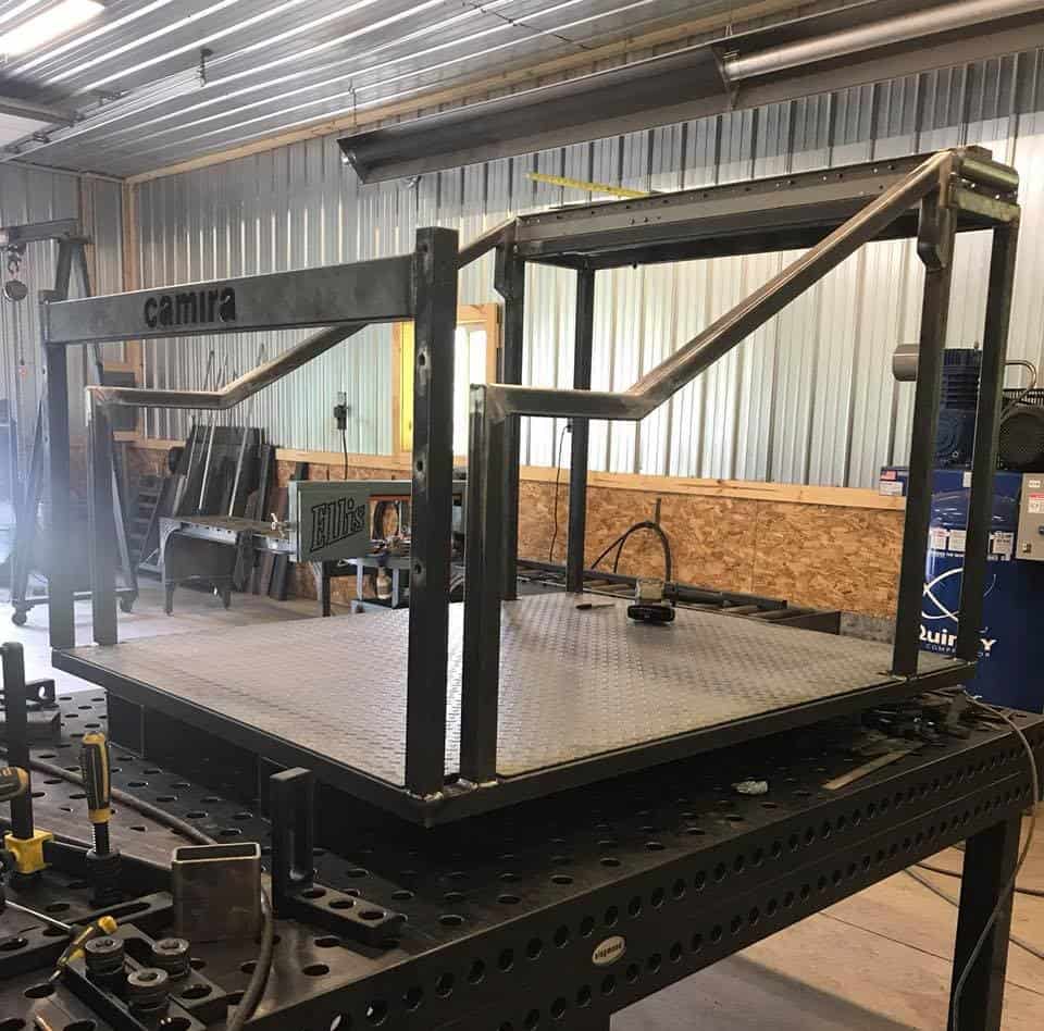 Metal fabrication platform with safety rails in workshop setting.