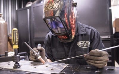 Welder in protective gear working on metal fabrication at Lynch's Metal Fab.