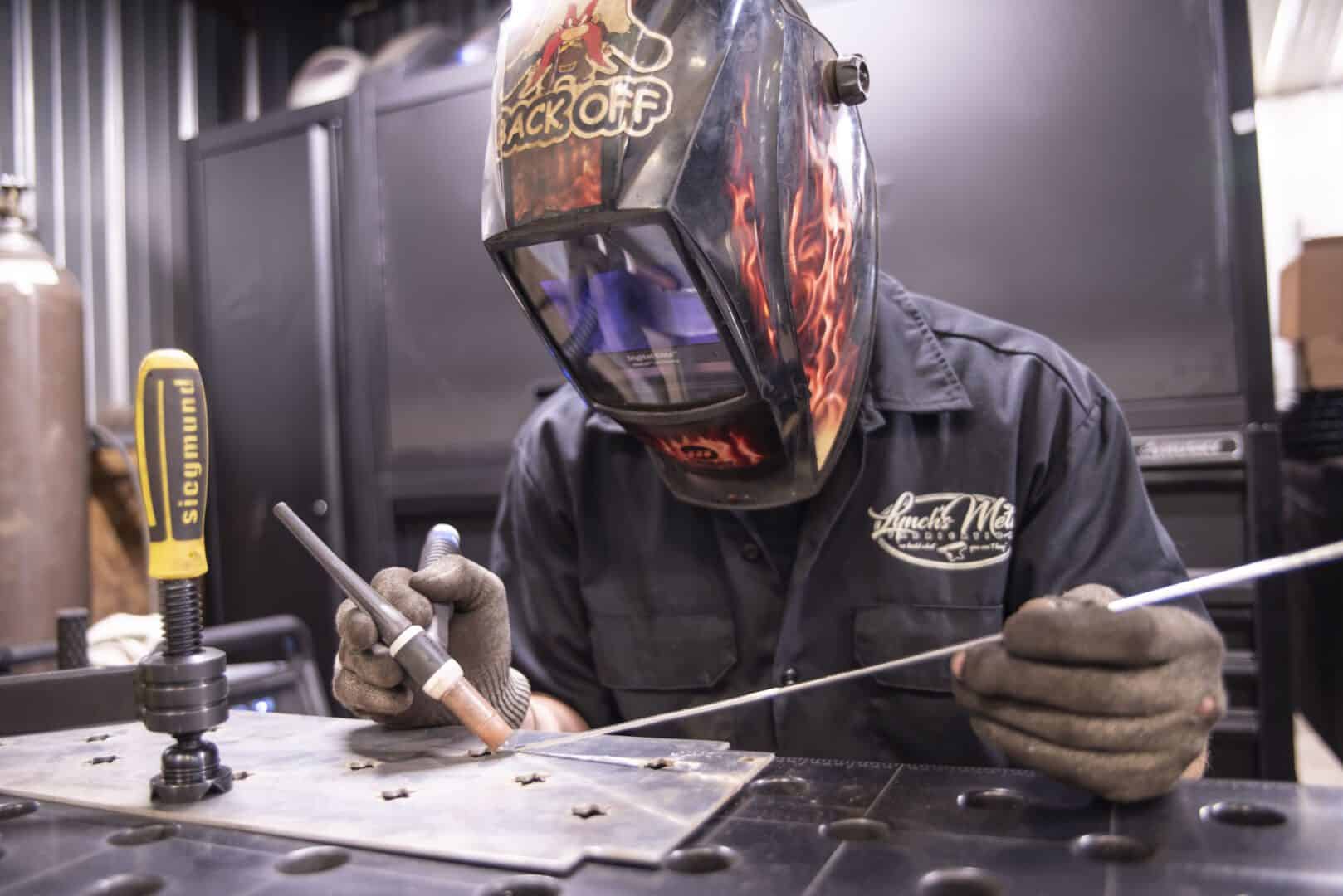 Welder in protective gear working on metal fabrication at Lynch's Metal Fab.