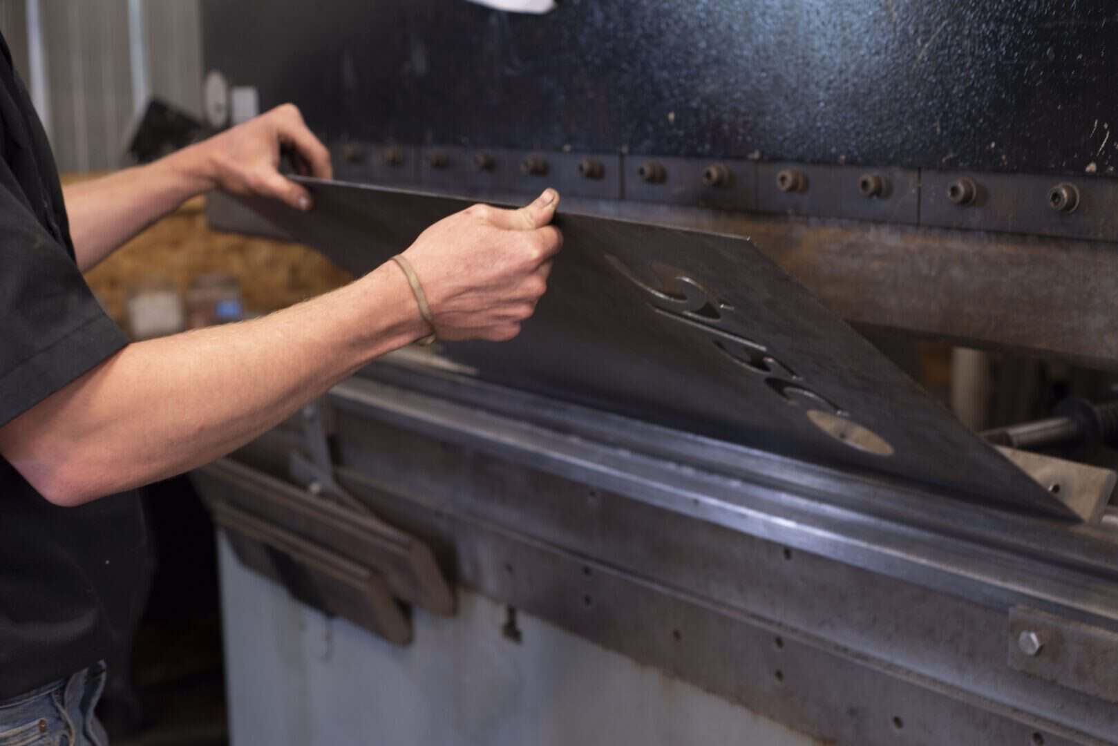 Worker handling metal sheet in a fabrication workshop.