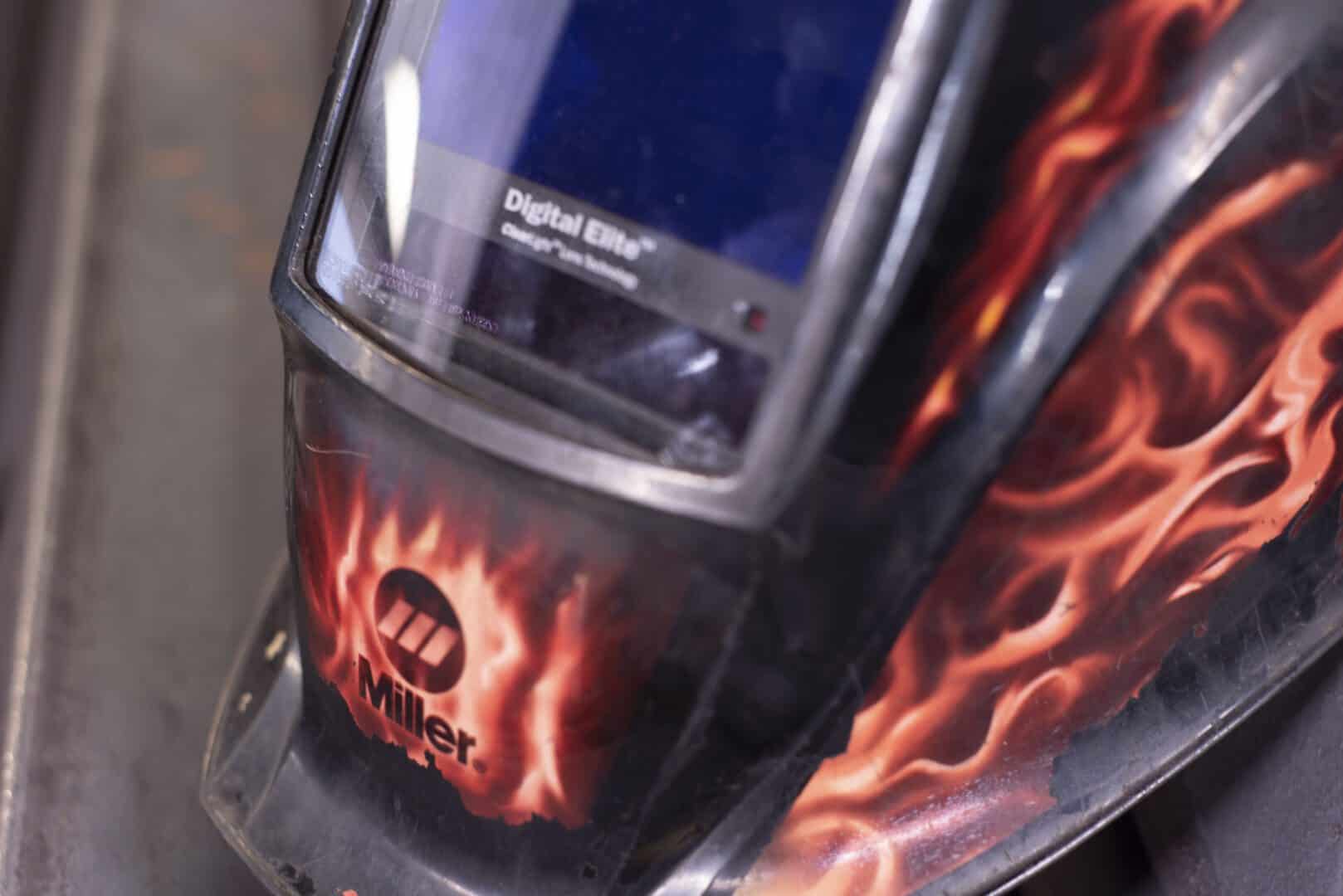 Welding helmet with flame design and Miller logo for safety.