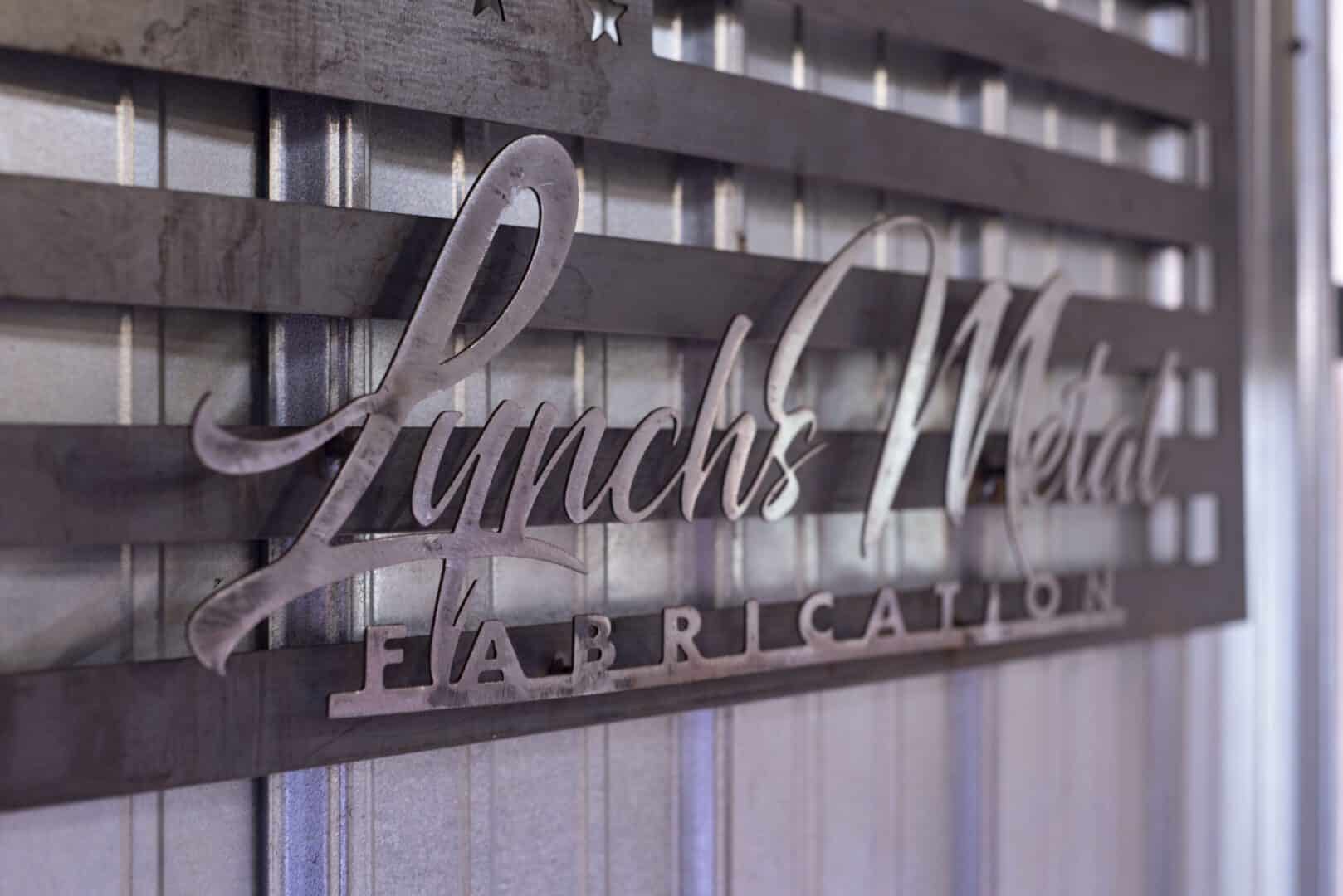 Metal sign reading Lynch's Metal Fab on a wooden background.
