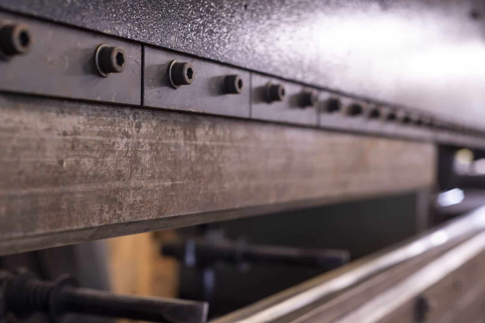 Close-up of metal fabrication machinery with bolts and metal surface.