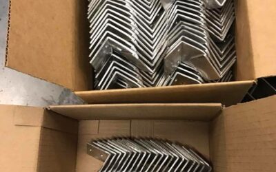Stacked metal corner brackets in cardboard boxes for fabrication or assembly.
