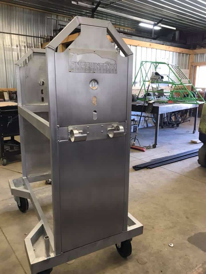 Stainless steel metal fabrication cart with wheels in workshop.