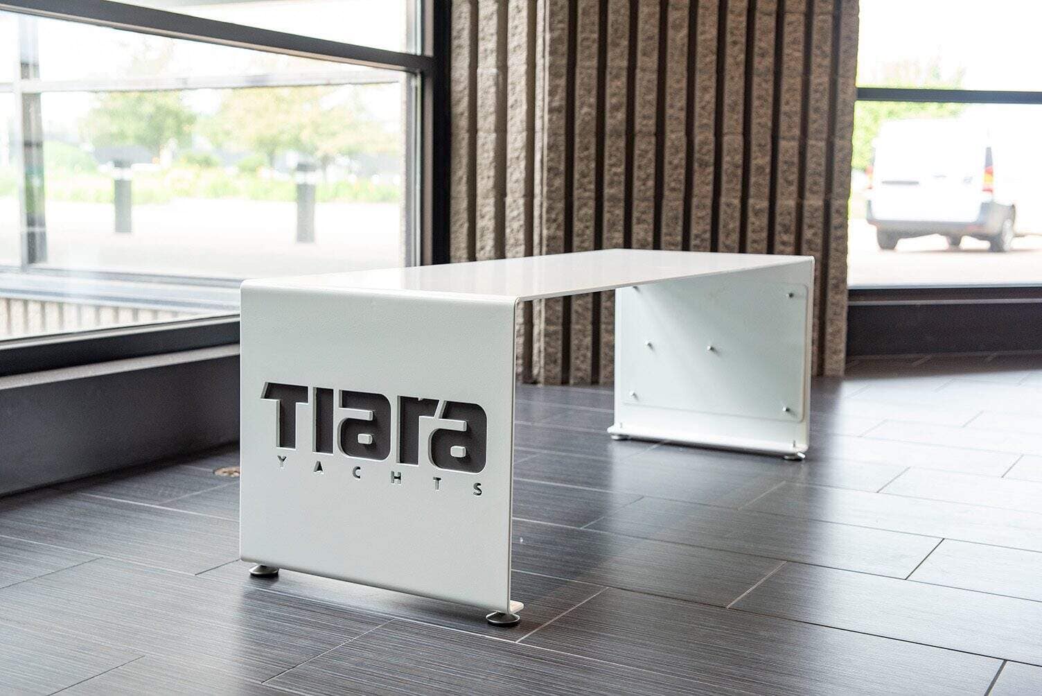White metal bench with Tiara Yachts logo in a modern indoor setting.