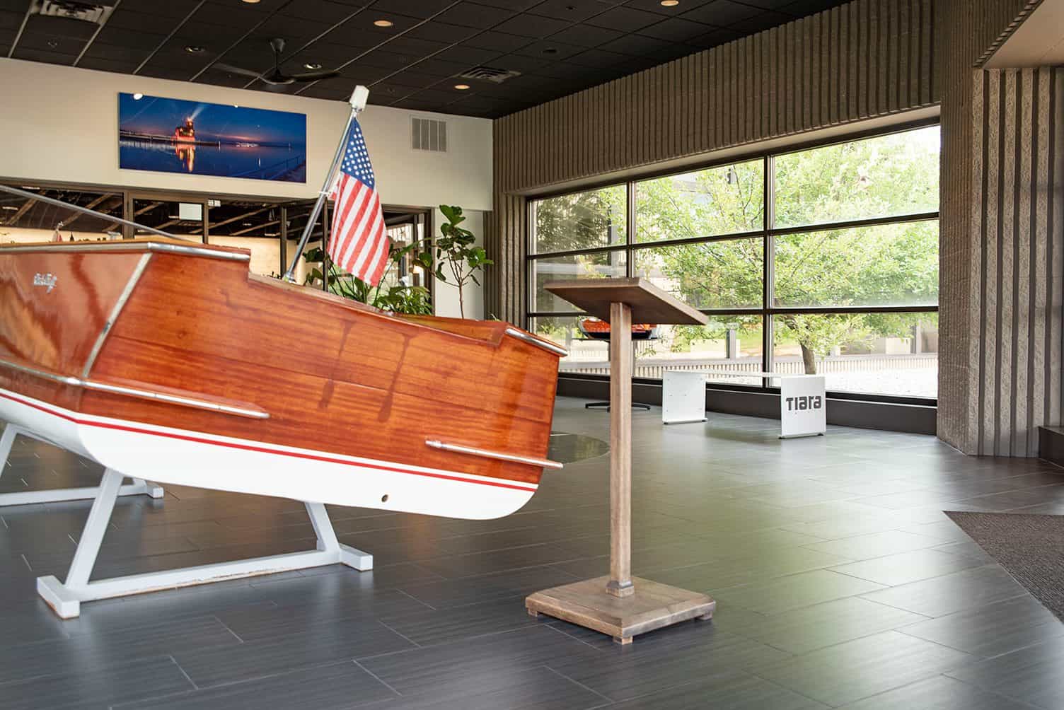 Wooden boat model on display at Lynch's Metal Fab showroom with large windows.