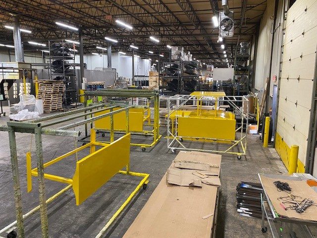 Industrial manufacturing area with metal fabrication equipment and yellow safety barriers.